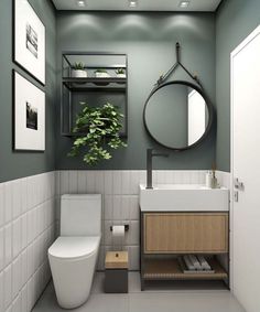 a white toilet sitting next to a sink in a bathroom under a mirror and potted plant