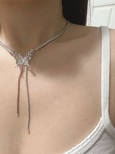 This exquisite necklace features a stunning white butterfly as its centerpiece. The butterfly, crafted with meticulous attention to detail, showcases delicate chains adorned with square-cut gems on both sides. These gems are meticulously set, adding a touch of elegance and sparkle to the design. From the bottom of the butterfly, two graceful chains hang, each embellished with small gems that mirror the pattern and brilliance of those on the chains. This necklace is a perfect blend of whimsy and sophistication, making it an ideal accessory for special occasions or to add a touch of elegance to everyday wear. Butterfly Chain Jewelry For Party, Butterfly Jewelry With Adjustable Chain For Parties, Butterfly Shaped Jewelry With Adjustable Chain For Parties, Butterfly Shaped Party Jewelry With Adjustable Chain, Crystal Jewelry With Butterfly Charm, Crystal Butterfly Charm Jewelry, Silver Jewelry With Butterfly Charm For Formal Occasions, Elegant Butterfly Shaped Jewelry With Adjustable Chain, Elegant White Butterfly Necklace In Cubic Zirconia