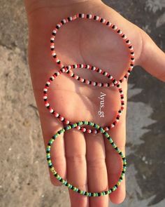 a hand holding a beaded bracelet with the letter e in it's middle