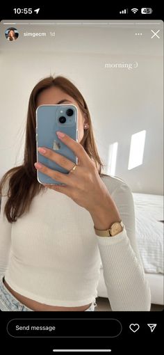 a woman taking a selfie with her cell phone in front of her face and wearing a white top