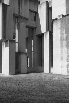 a black and white photo of a building made out of concrete blocks on the grass