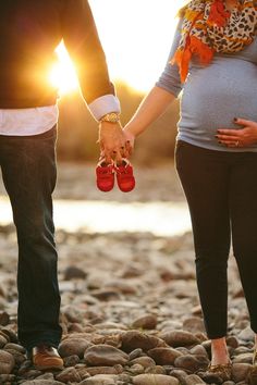 a pregnant couple holding hands while standing next to each other