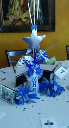 a centerpiece with blue streamers and stars sits on a table in front of a painting