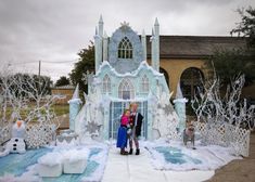 two people are standing in front of a fake ice castle with snowmen and trees