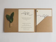 an open pocketfold wedding card with a green leaf on it