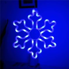 a lighted snowflake sitting in the corner of a room with blue lighting on it