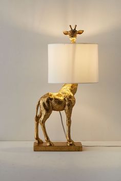 a golden giraffe lamp with a white shade on it's head and neck