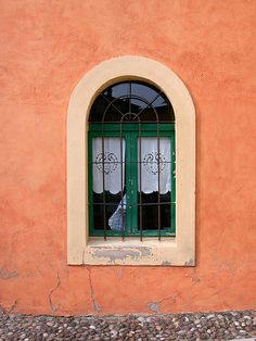 a window with bars on the side of it in front of an orange stucco wall