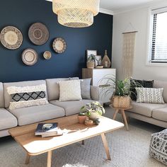 a living room filled with lots of furniture next to a wall covered in plates and plants