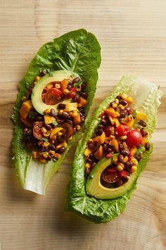 two lettuce wraps filled with beans and avocado on top of a wooden table