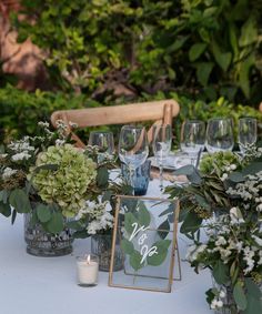 the table is set with vases, candles and flowers for an outdoor wedding reception