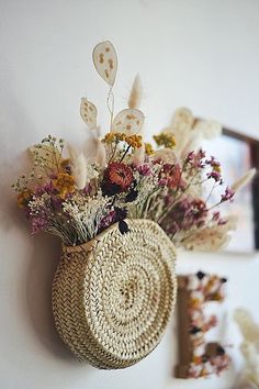 a basket with flowers hanging on the wall next to a mirror and other things in front of it