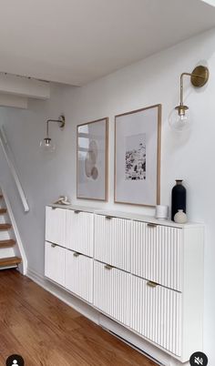 a white dresser sitting in the middle of a living room next to a stair case