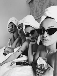 four women in towels and sunglasses on a bed