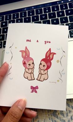 a person holding up a card with two rabbits on it and the words me & you