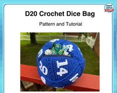 a blue crochet dice bag sitting on top of a red bench with the words d20 crochet dice bag written across it