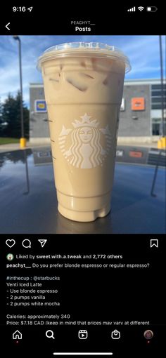 a cup of coffee sitting on top of a table next to a window with the words starbucks