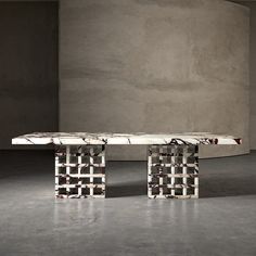 a marble table sitting in front of a concrete wall with an abstract design on it