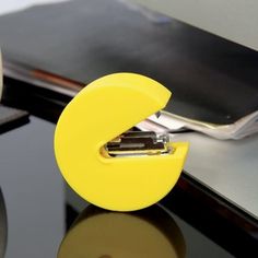 a yellow plastic object sitting on top of a black table next to a laptop computer