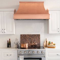 a stove top oven sitting inside of a kitchen next to white cabinets and counter tops