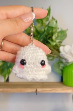 a hand holding a keychain with a small white sheep on it's face