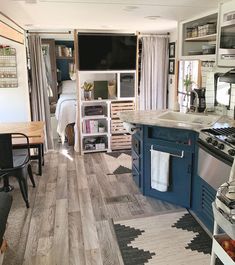 a kitchen and dining area in an rv with wood flooring, white walls and blue cabinets