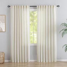 a white curtain hanging on the side of a window next to a potted plant