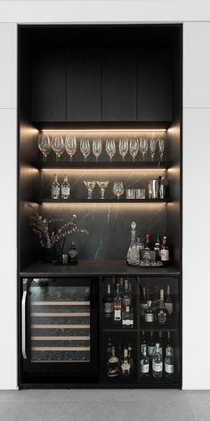 a black cabinet with wine glasses and liquor bottles