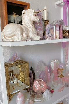 a white shelf topped with lots of different types of crystals and figurines on top of it