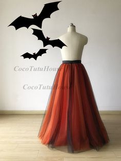 an orange and black tulle skirt with bats on the top is displayed in front of a white wall