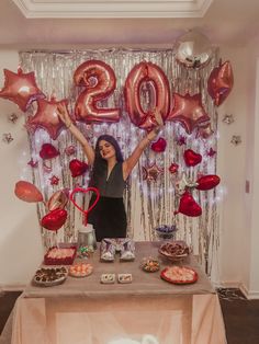 a woman standing in front of a table with lots of food and balloons on it