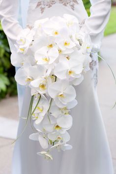 a bride holding a bouquet of white orchids