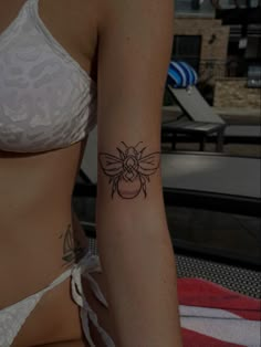 a woman with a bee tattoo on her left arm and right arm behind her back