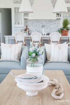 a table with plates and flowers in a vase on top of it next to a couch