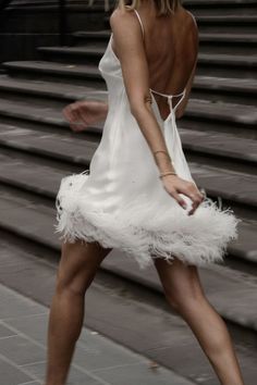 a woman in a white dress walking down the street