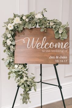 a welcome sign with greenery and white flowers