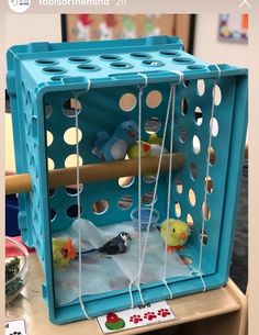 a bird in a cage sitting on top of a table next to a toy mouse