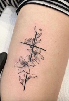 a woman's thigh with a cross and flowers tattoo on the side of her leg