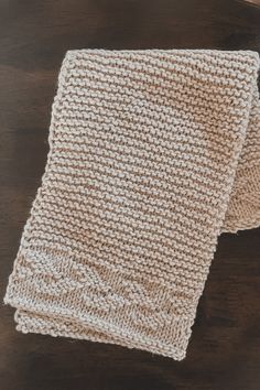 two white knitted napkins sitting on top of a wooden table