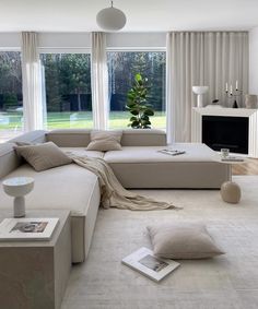 a living room filled with white furniture and large windows