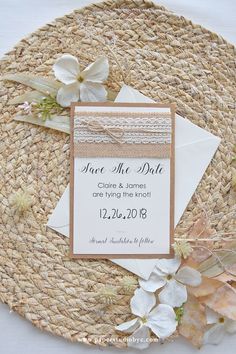 a wedding save the date card on top of a place mat with flowers around it