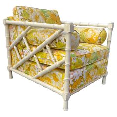 a white bamboo couch with yellow and green floral upholstered cushions on it's back