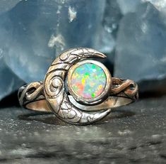 Crescent moon opal ring in solid sterling silver with a Celtic knot band. This ring is made to order in your size. The stone measures 6mm in size and the moon in 12mm. These are man made opals and they are absolutely stunning. Custom orders are welcome. Feel free to contact me with questions or comments.  Ring size. Made to order in your size. Handmade Mystical Opal Ring, Adjustable Celestial Opal Ring, Celestial Silver Opal Ring, Celestial Style Opal Ring, Adjustable Round Opal Ring Spiritual, Adjustable Round Opal Ring, Spiritual Style, Adjustable Round Opal Ring For Spiritual Purposes, Spiritual Adjustable Opal Ring, Mystical Opal Ring For Anniversary