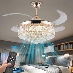 a person holding a remote control in front of a bed with a chandelier