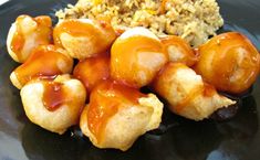 a black plate topped with fried food and rice