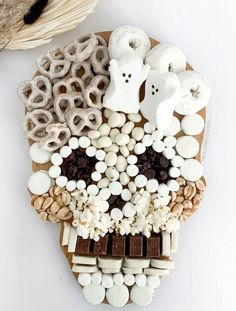 a wooden board topped with marshmallows and other items next to a wicker basket