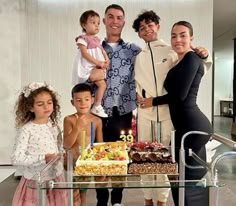 a group of people standing in front of a table with a cake and candles on it