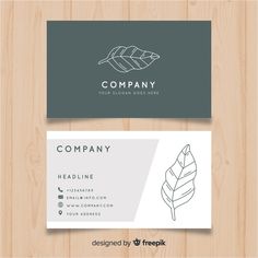 a business card with a leaf on the front and back, sitting on top of a wooden