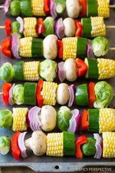 corn on the cob and vegetable skewers are ready to be grilled