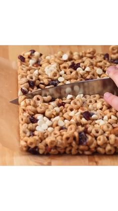 someone is cutting into some cereal bars with a knife